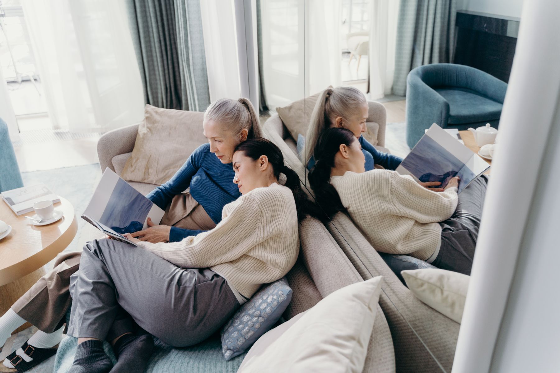 An adult daughter reading at home with her older mother